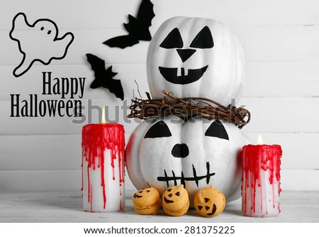 White Halloween pumpkins, candles and candies, on white wooden background