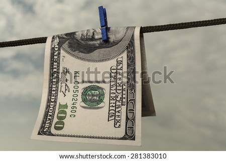 One hundred american dollar drying on string with cloudy  sky
