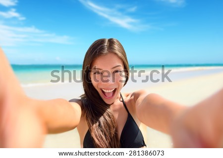 Selfie fun woman taking photo at beach vacation. Summer holiday girl happy at smartphone camera taking self-portrait on her travel vacations on pristine paradise beach.