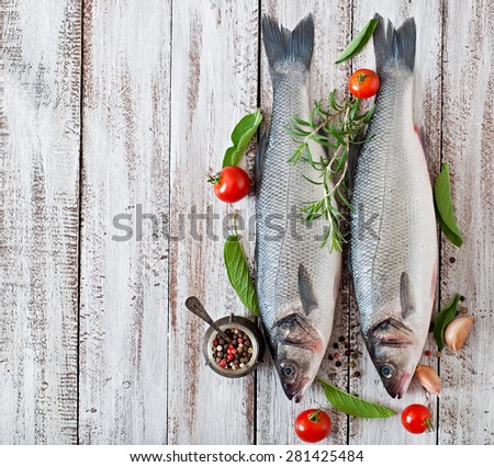 Two raw seabass with spices on an old wooden background. Top view