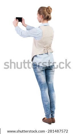 back view of standing young beautiful  woman  in vest and using a mobile phone. Rear view people collection.  backside view of person.  Isolated over white background. Girl doing selfie on your phone.