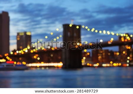 Bokeh photo of New York City Brooklyn Bridge with downtown skyline over East River at night 