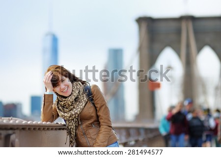 Beautiful young girl on Brooklyn Bridge with skyscrapers on background