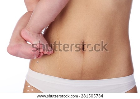 Woman's belly after six months of birth of baby and the baby's legs, on white background
