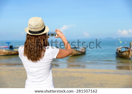 Woman taking photos with smartphone at Railay Beach, Krabi, Thailand.