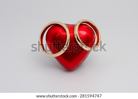 Wedding rings placed on a red heart shaped candy
