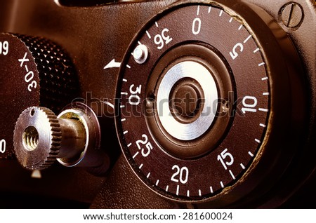 Fragment of an old film camera. Top view of the dial of exposure, the shutter button and the frame counter. Close up view. Macro. Vintage photo. Toning.