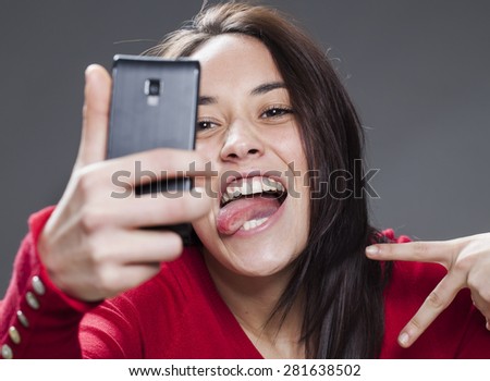 gorgeous mixed-race young woman making a face for her self-portrait on cell phone