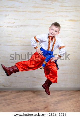 Ukrainian talented child performing a traditional dance move with a leap in mid air while wearing folk costume during a cultural artistic representation