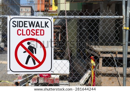 Sidewalk Closed Sign On A Chain Link Fence.