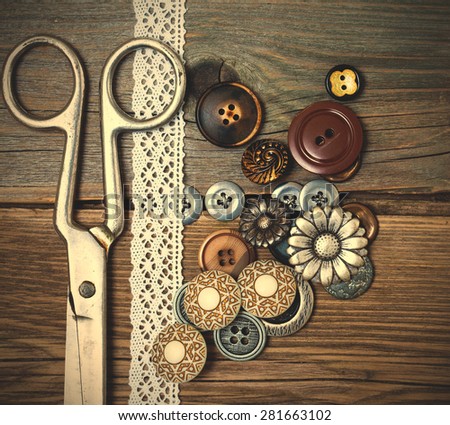 vintage buttons, tape lace and a tailor scissors on a textured surface of old boards. instagram image filter retro style