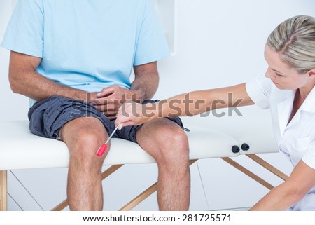 Doctor checking reflexes of the knee of her patient in medical office