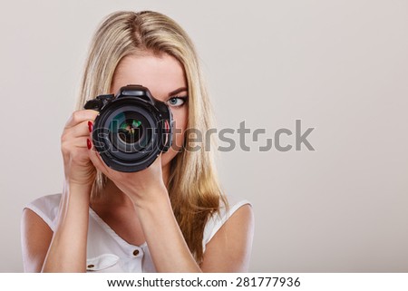 Photographer girl shooting images. Attractive blonde woman taking photos with camera.