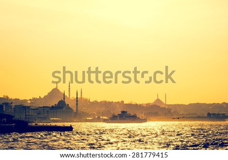 Silhouettes of turkish steamboat and minaret of mosque in Istanbul on sunset. Skyline with soft light effect - travel concept in retro style. Cityscape of old town in a fog, Istanbul seaside. Royalty-Free Stock Photo #281779415