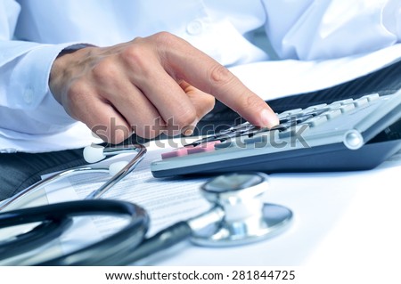 closeup of a young caucasian healthcare professional wearing a white coat calculates on an electronic calculator Royalty-Free Stock Photo #281844725