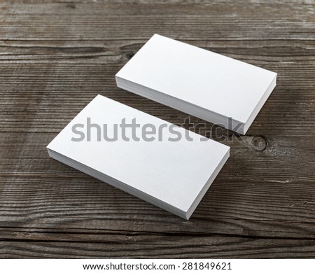 Two stacks of blank business cards on a dark wooden background. Template for branding identity. Shallow depth of field. Selective focus.