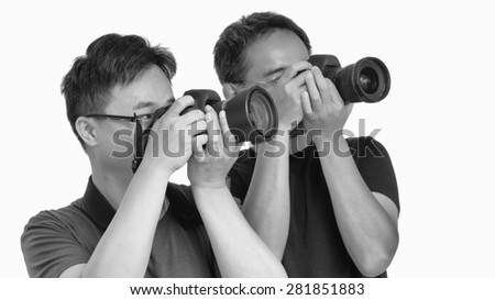 Two asian photographers shooting the same subject. Isolated on white.