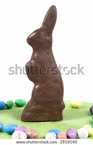 Chocolate easter bunny standing amongst colorful eggs