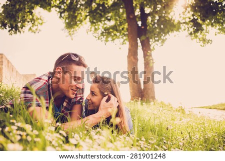Happy young couple lying at the grass 