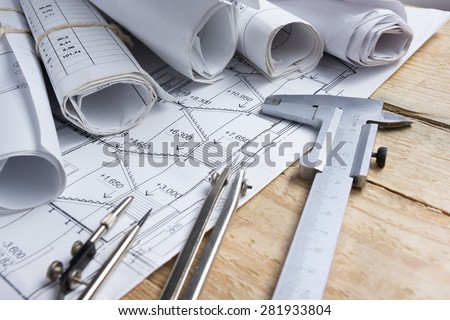 Architectural project, blueprints, blueprint rolls and  divider compass, calipers on vintage wooden background. Construction concept. Engineering tools. Copy space Royalty-Free Stock Photo #281933804