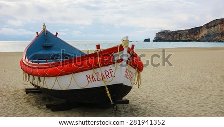 Traditional colorful  boat on the beach of Nazare (Portugal) at evening dusk.