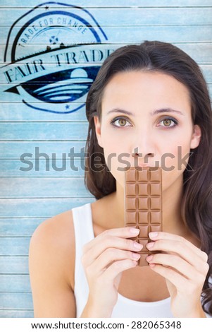 Pretty brunette eating bar of chocolate against wooden planks