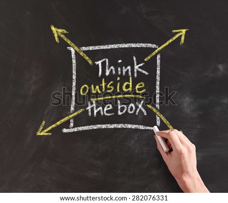 Four arrows getting out of a square towards different directions with the written motivational message to think outside the box, drawn by hand on blackboard with copy space