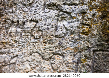 Moss-grown surface of the old stone cross with engraved Old Church Slavonic inscriptions. Kyiv, Ukraine. Close up.