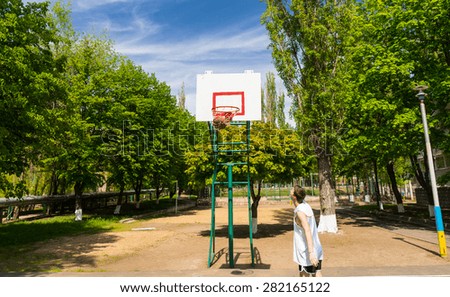 Young Athletic Man Watching Successful Shot with Ball in Net on Basketball Court in Lush Green Park