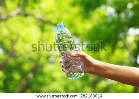 Woman hand holding water bottle against green background