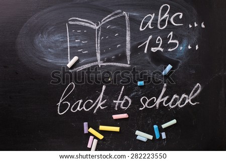 Chalk drawing and pieces of chalk  on blackboard. Educational concept. Phrase back to school.