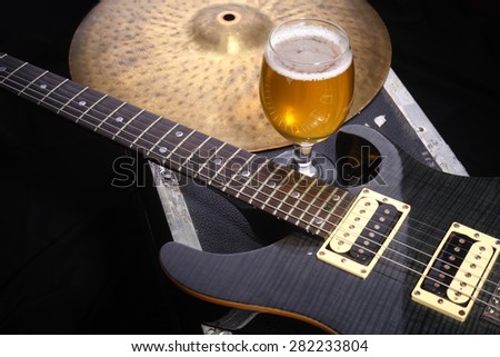 Glass full of light beer standing on a case with some music equipment Royalty-Free Stock Photo #282233804