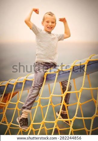 Little boy enjoying summer holidays on the sea. Retro style and warm filtered picture.