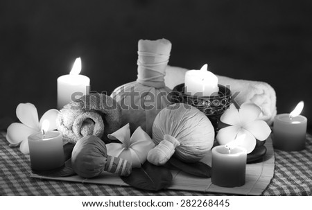 Black and white picture of  Thailand traditional medicine,
The herbal ball for massage and spa is decorated with frangipani and candles.
