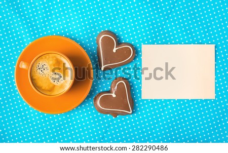 ceramic cup with coffee espresso, tablet for text and two chocolate marzipan candy hearts on a blue background, love concept, have a nice day, good morning, good day, happy Valentine's Day, top view