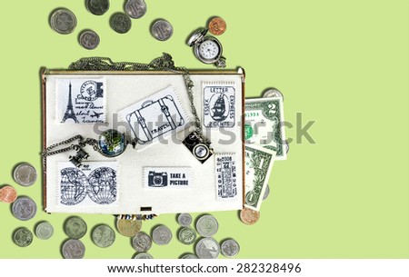 Wooden travel box with stickers of fabric, banknotes and coins, watches, metal pendants in the form of the globe and the camera on an isolated background. Top view