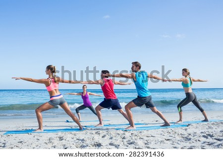 Friends doing yoga together with their teacher at the beach Royalty-Free Stock Photo #282391436
