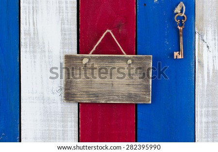 Blank rustic sign and bronze skeleton key hanging on red, white and blue wooden background