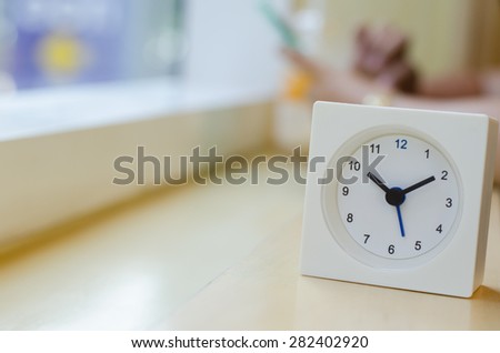 The clock displays the time ten o'clock ten minutes on mini bar side of the window  At coffee shop in  Bangkok  with blurred background image women are used  smart phone ,