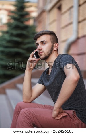 Outdoor portrait of modern young man with mobile phone