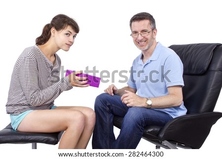 Teenage daughter giving a surprise gift to her single father.  They are isolated on a white background.  The image depicts Father's Day