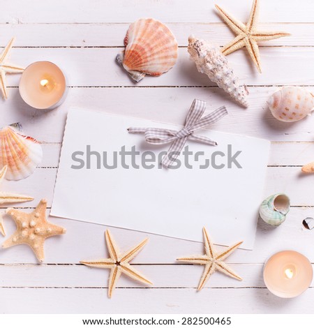 Marine items and candles  and tag for text on  white painted wooden background. Sea objects on wooden planks. Selective focus. Place for text. Square image. 