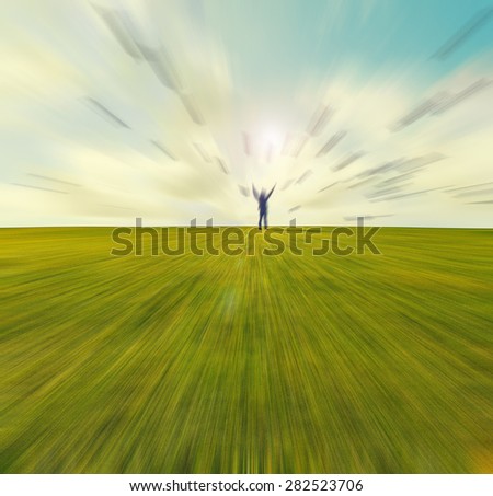 Silhouette of young man standing with hands open wide on the top of green field under sunset skies ,freedom , success and freedom concept