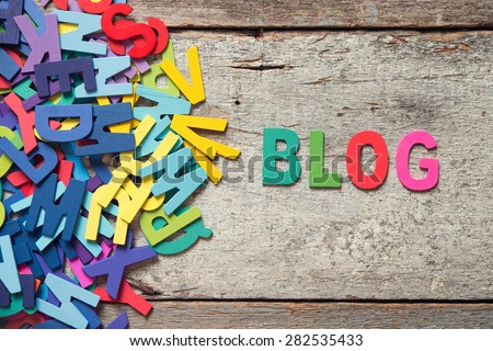 The colorful words "BLOG" made with wooden letters next to a pile of other letters over old wooden board. Royalty-Free Stock Photo #282535433