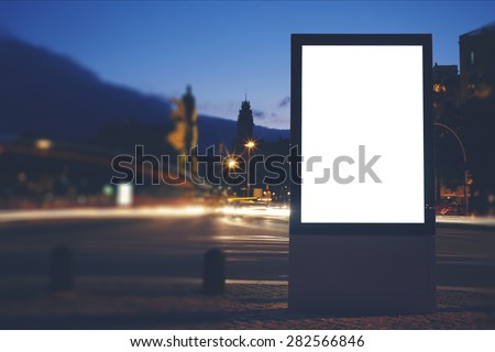 Illuminated blank billboard with copy space for your text message or content, public information board in night city with beautiful dusk on background, advertising mock up banner in metropolitan city