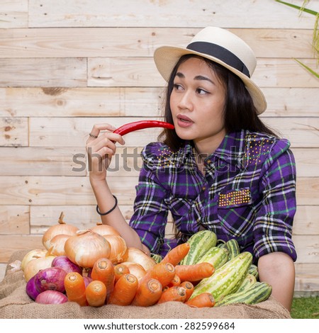 Beautiful woman with chili pepper in mouth. and a basket of vegetables in front of her.