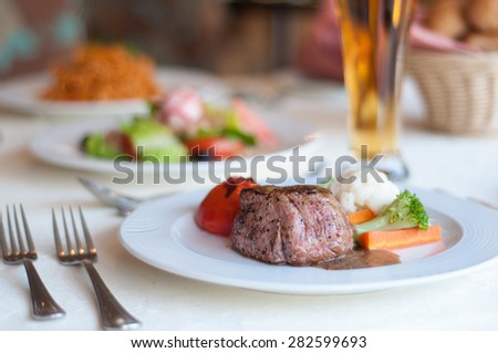 Gourmet cuisine at restaurant. Beefsteak and green vegetables platter on  table.