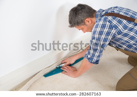 Close-up Of A Craftsman Fitting Carpet On Floor Royalty-Free Stock Photo #282607163