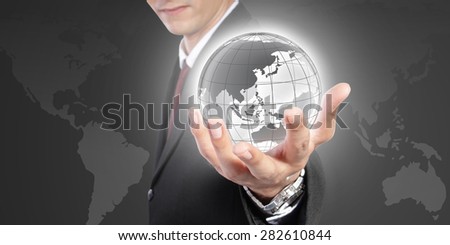 The world is in your hand. Conceptual image of global control, power and domination. A man in formal wear holding a globe inside his hand