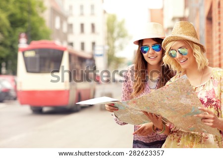 A picture of two girl friends using a map in the city